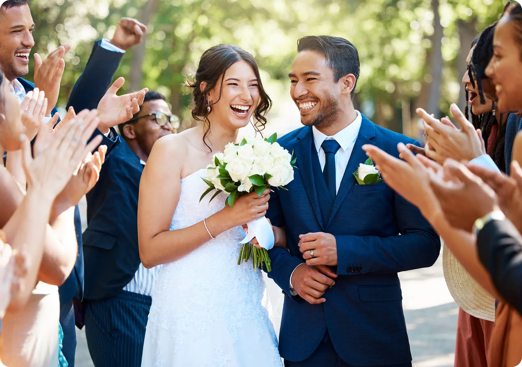 Bride and groom smiling, surrounded by guests.
