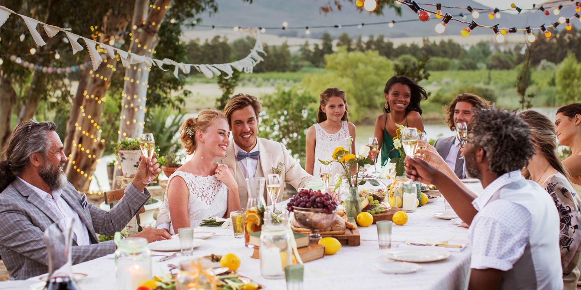 Outdoor wedding reception with guests toasting.